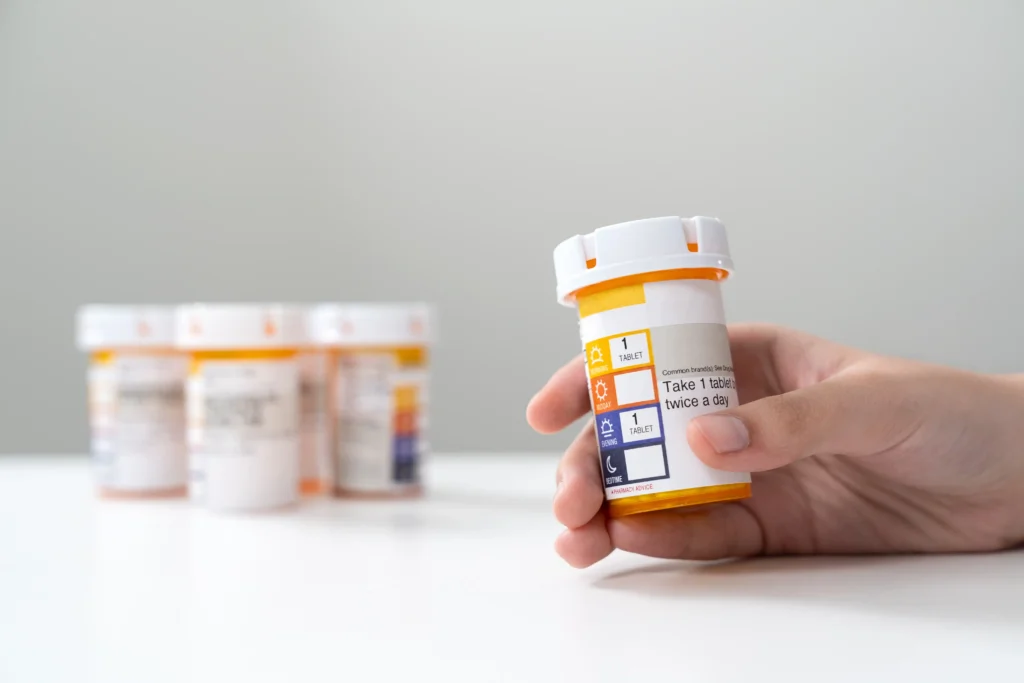 Hand Holding Guanfacine Medication Bottle