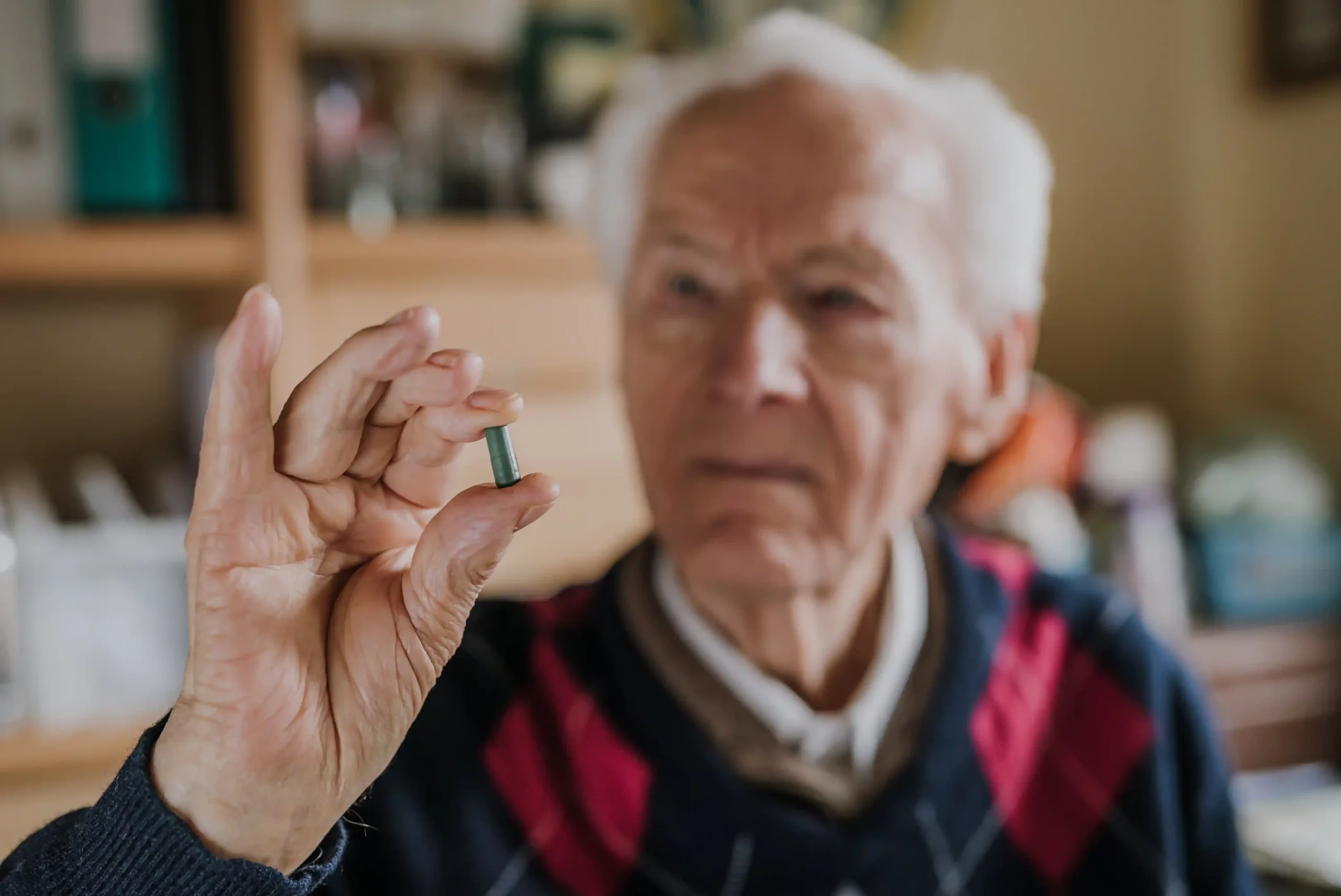 Old person holding a Lipitor pill.